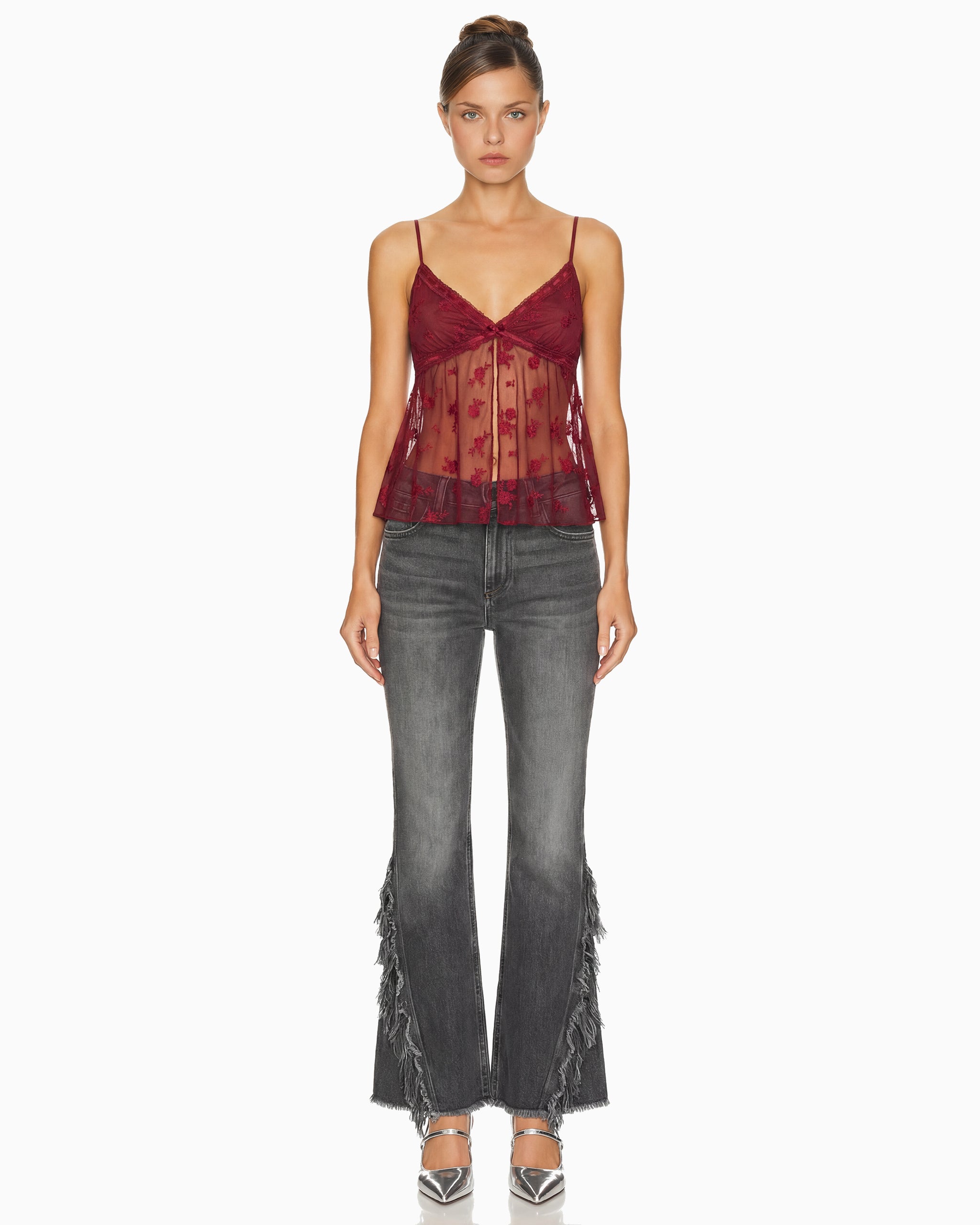 Modelo de frente veste a Calça Punk flare em jeans cinza lavado, com franjas desfiadas descendo pelas laterais das pernas