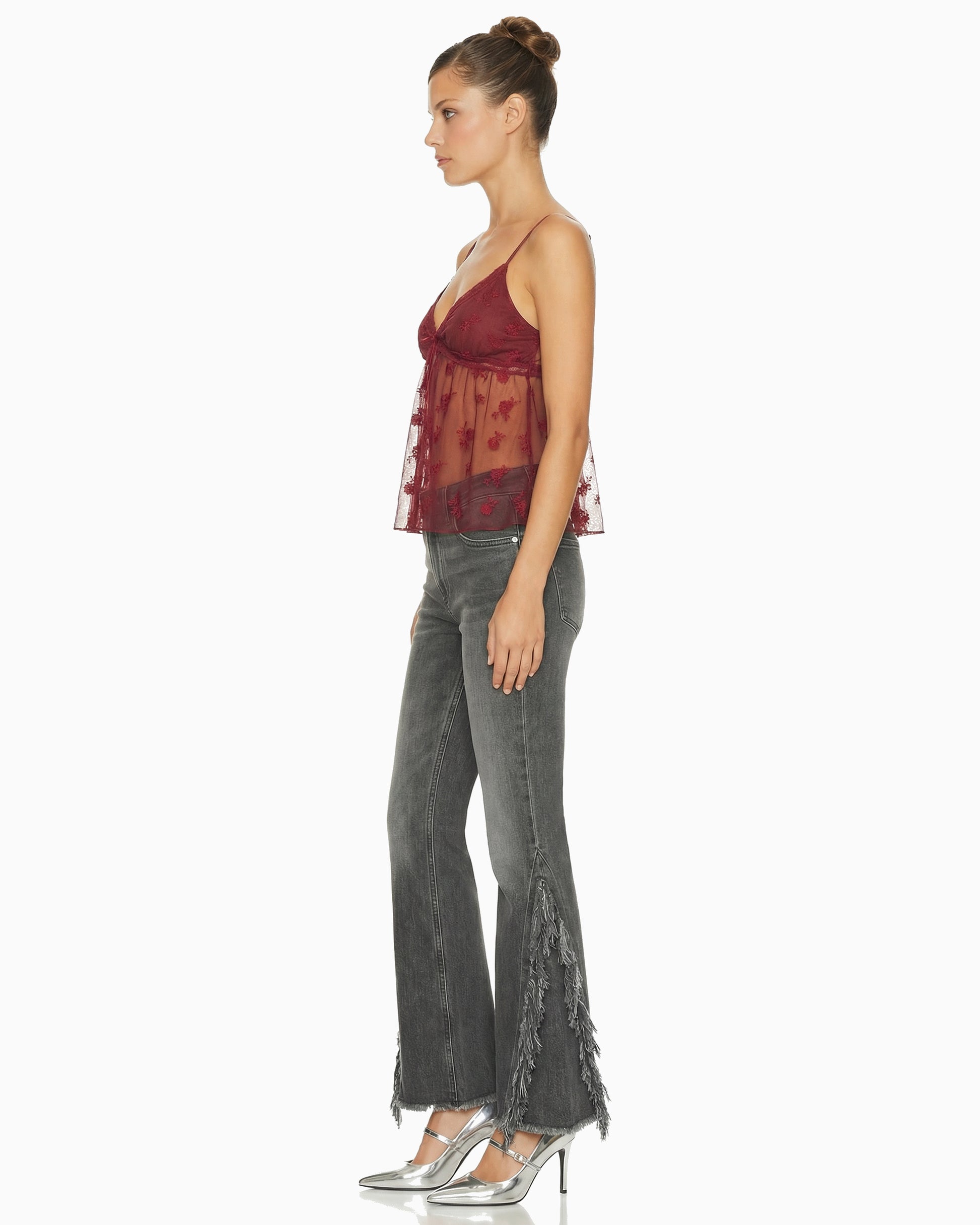 Vista lateral da Calça Punk flare em jeans cinza lavado na modelo, mostrando as franjas desfiadas na lateral da perna