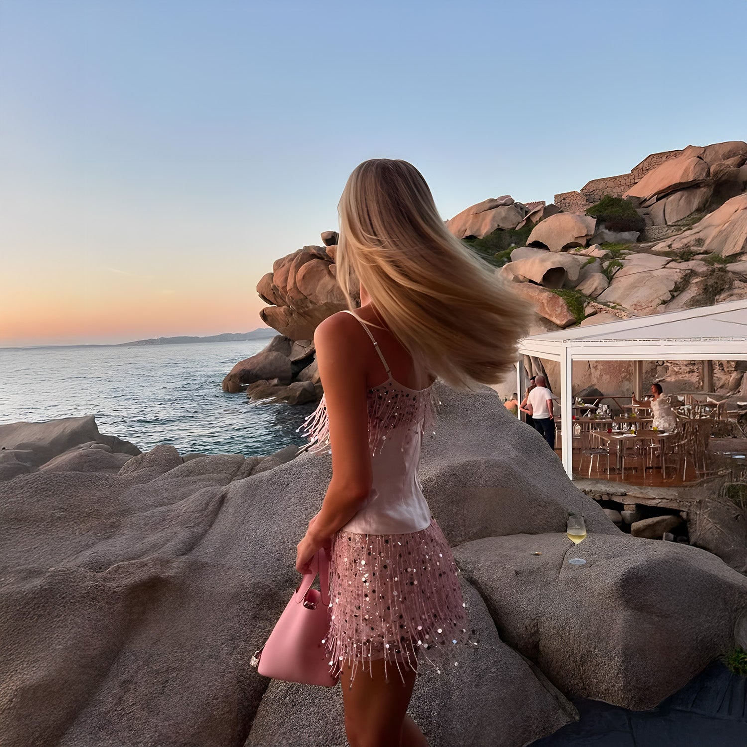 Vista de costas do Conjunto Pink Sparkles rosa na modelo, com alcinhas finas e franjas de paetês na saia
