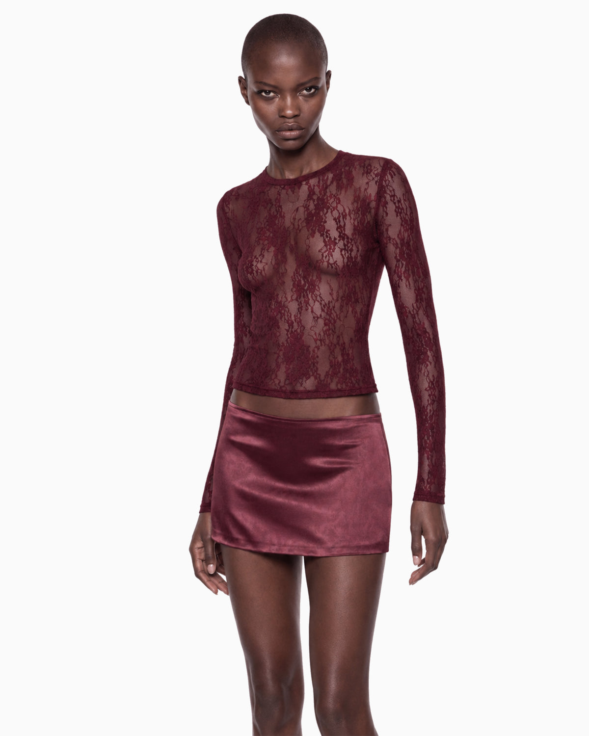 Modelo de frente com a Blusa Manga Longa Renda Haze vinho transparente sobre minissaia de cetim vinho