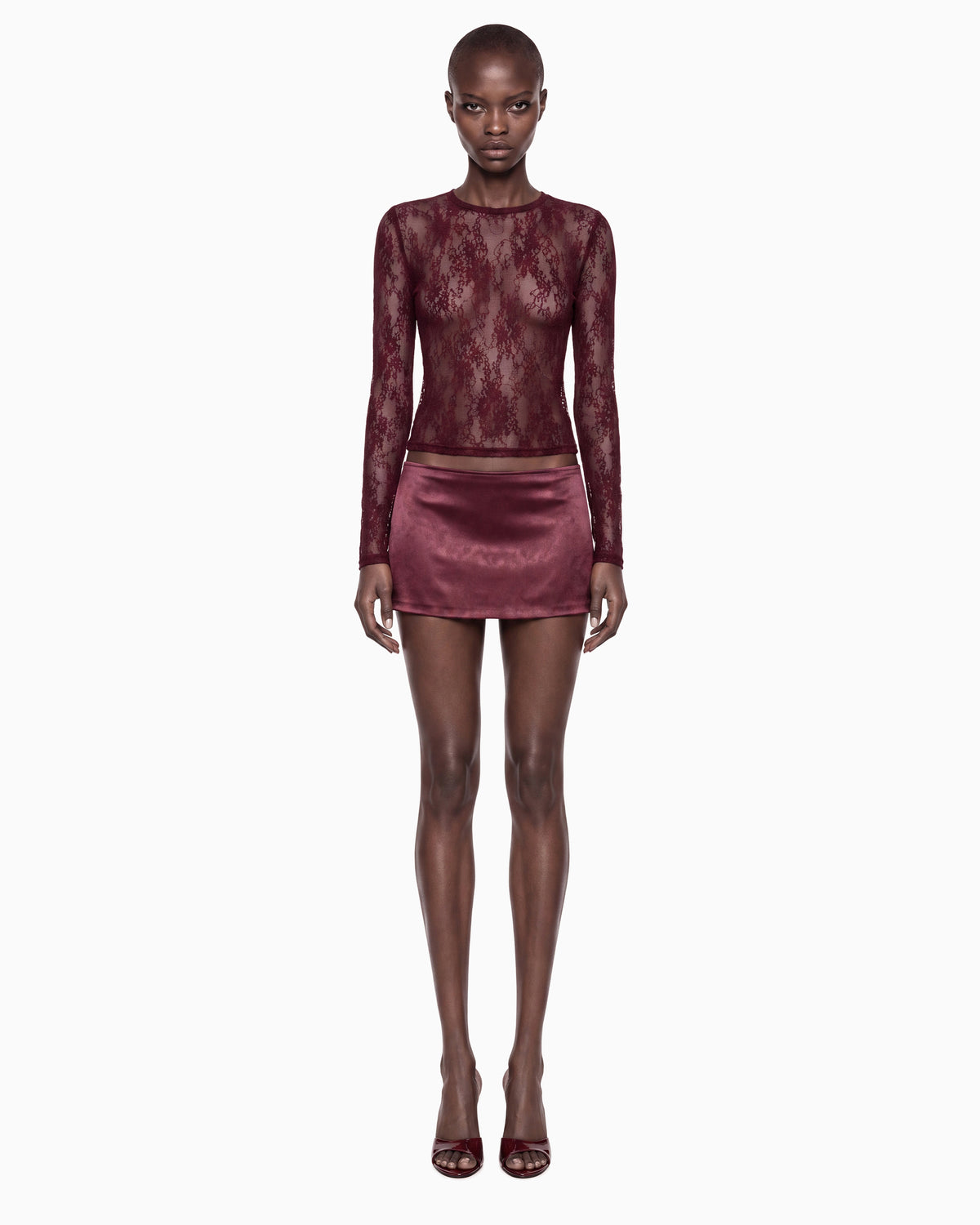 Modelo de corpo inteiro de frente com a Blusa Manga Longa Renda Haze vinho e minissaia de cetim