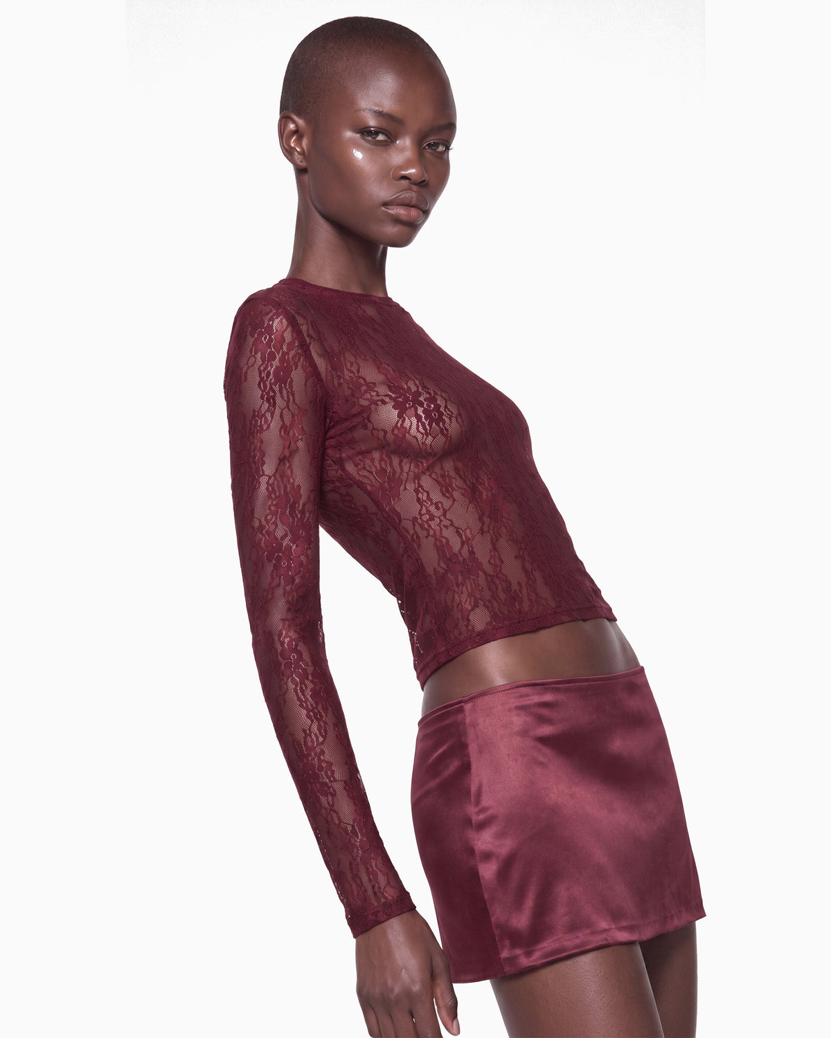 Vista lateral da Blusa Manga Longa Renda Haze vinho na modelo, renda floral transparente e barra cropped