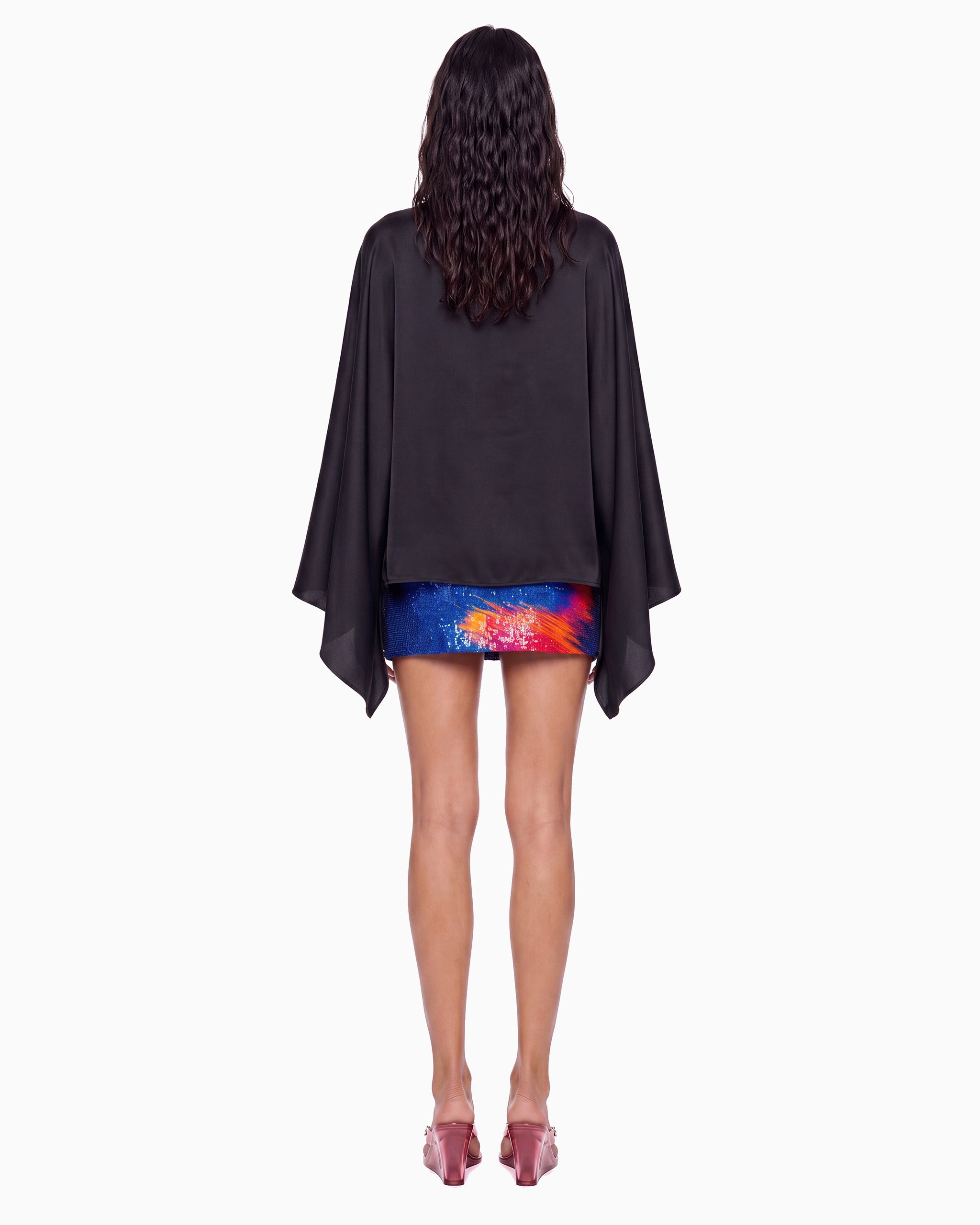 Vista de costas da Blusa Manga Morcego Crepe Ivo preta na modelo, corpo solto e pontas das mangas caídas