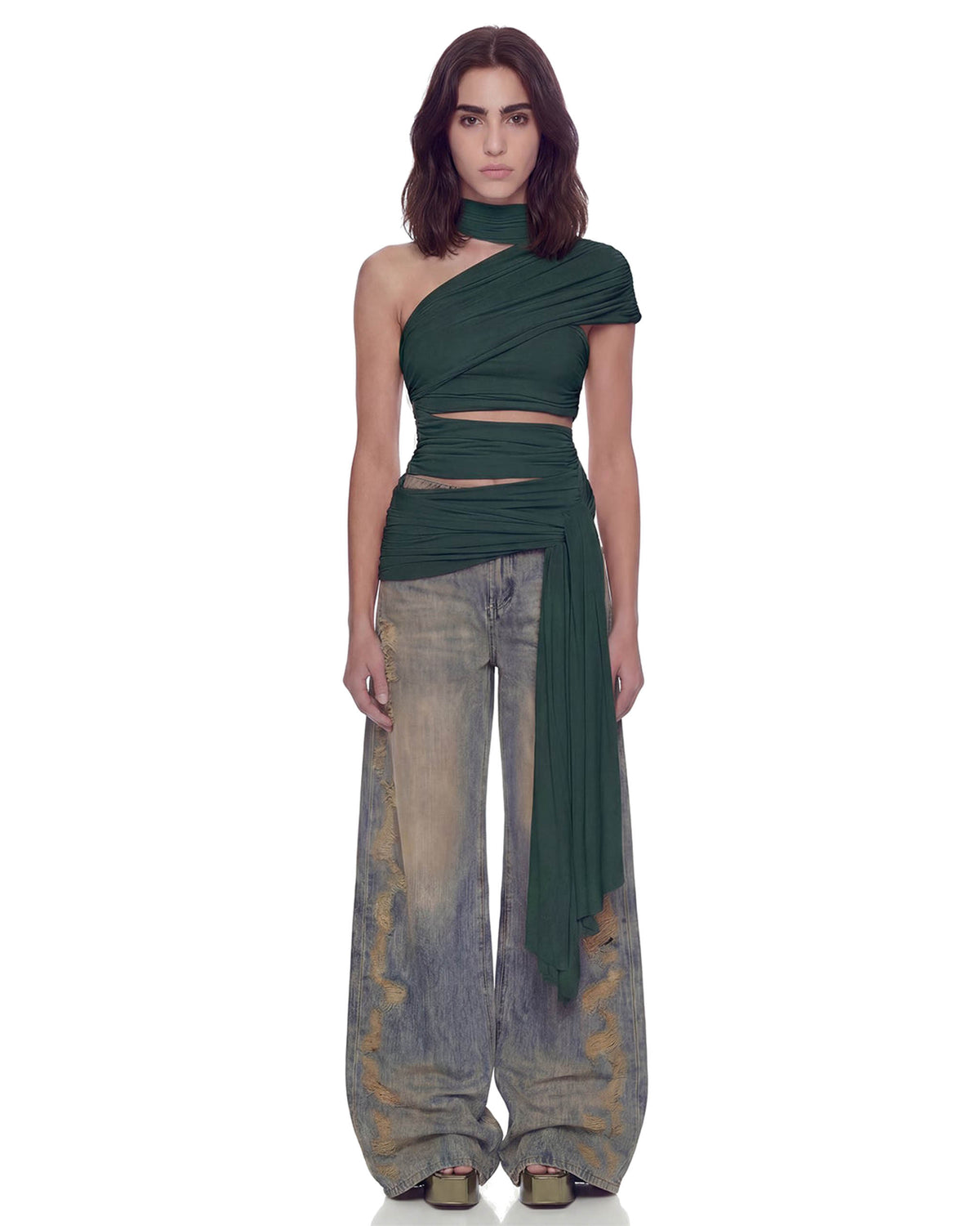 Modelo de frente com a Blusa Ombro Drapeado Hexa verde cropped, gola choker e ombro único, combinada com calça jeans
