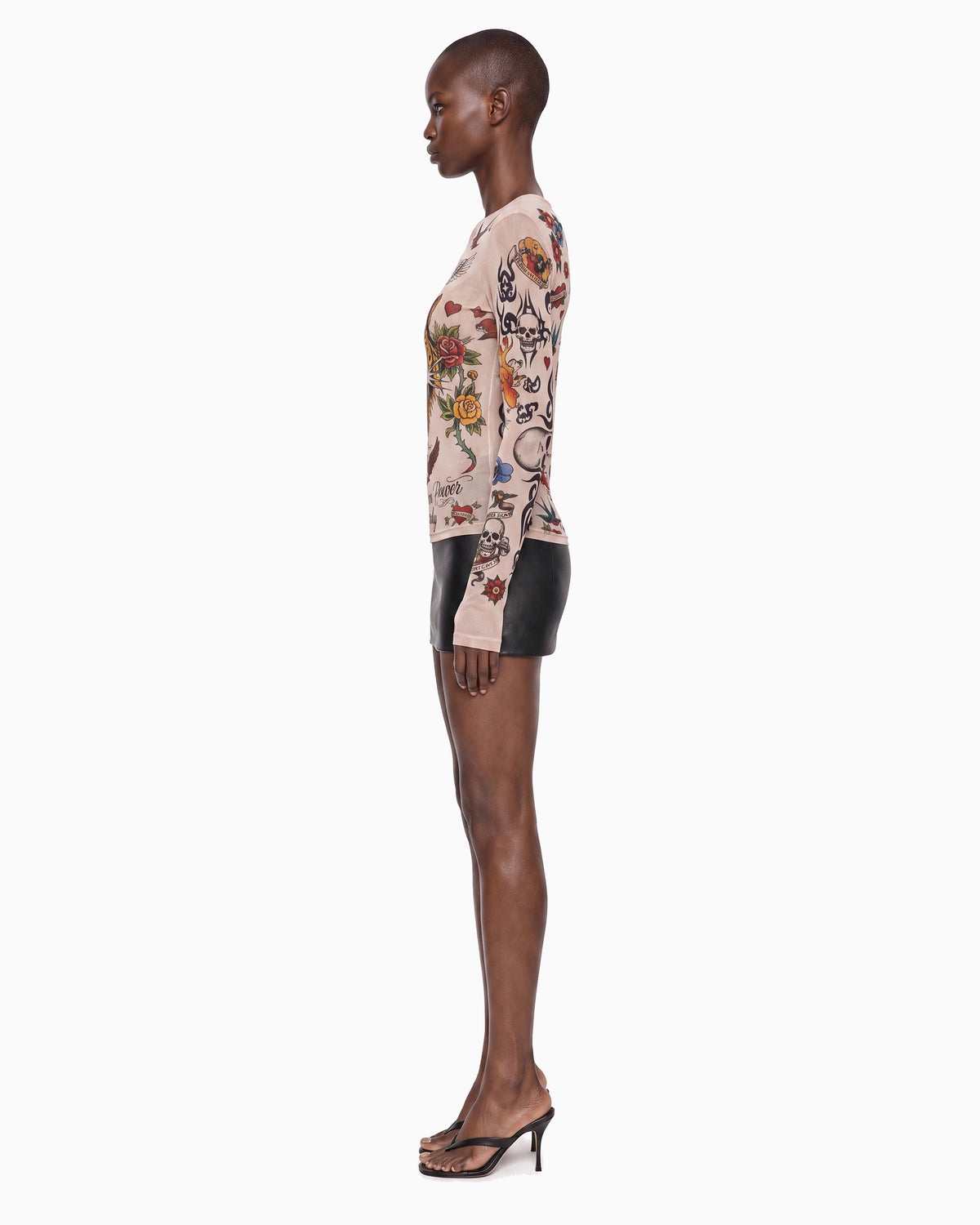 Vista lateral da Blusa Tule Tigre bege, manga longa justa toda estampada de rosas e caveiras