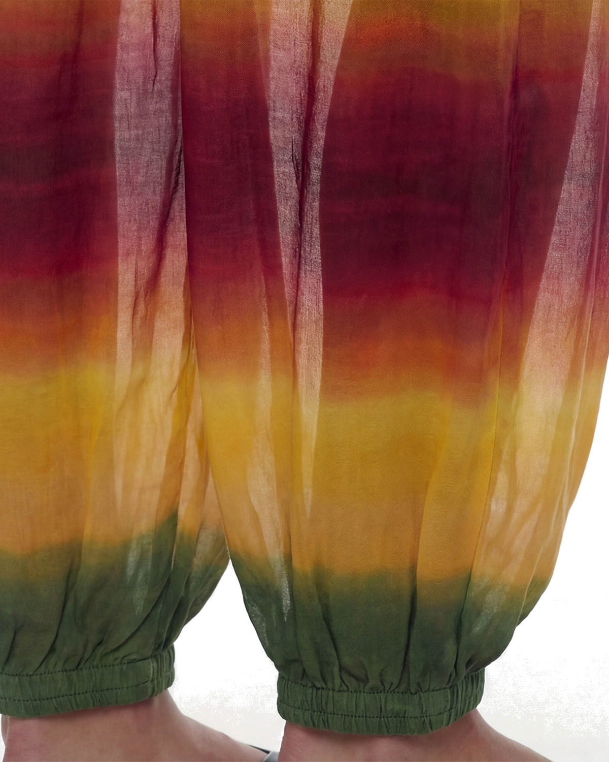Close da barra da Calça Aladdin Tule Ginga com punho elástico verde e degradê amarelo e vermelho no tule