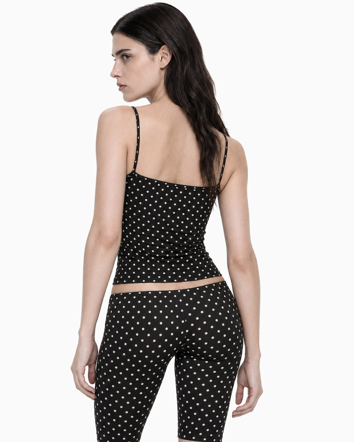 Costas da Calça Capri Cintura Baixa Poá preta com poás brancos na modelo