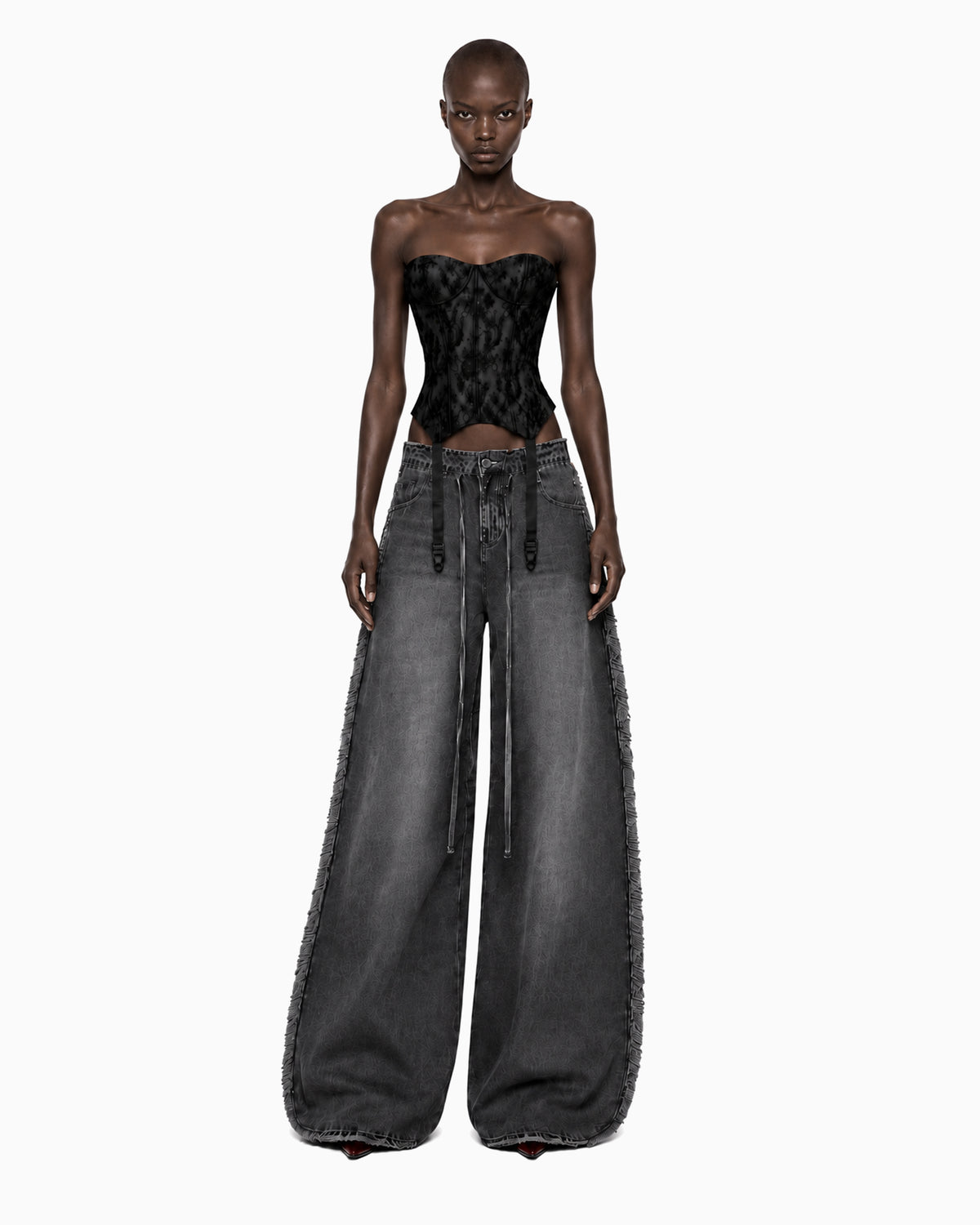 Modelo de frente com Calça Jeans Preta Desfiada, braços soltos e cordão comprido caindo da cintura