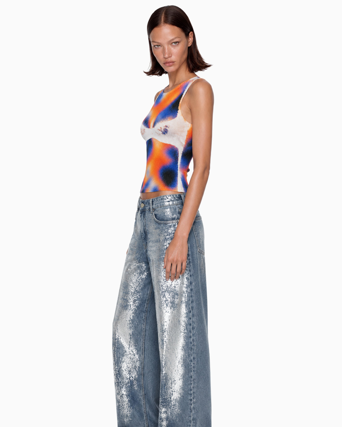 Vista três quartos da Calça Jeans Wide Foil Prata na modelo, destacando o brilho metalizado