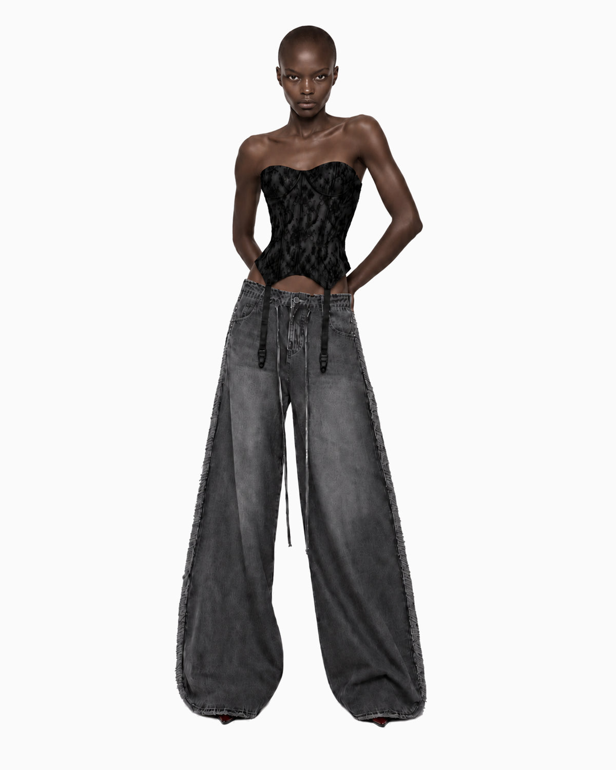 Modelo de frente com Corset Renda Haze preto tomara que caia, mãos atrás do corpo e calça jeans grafite