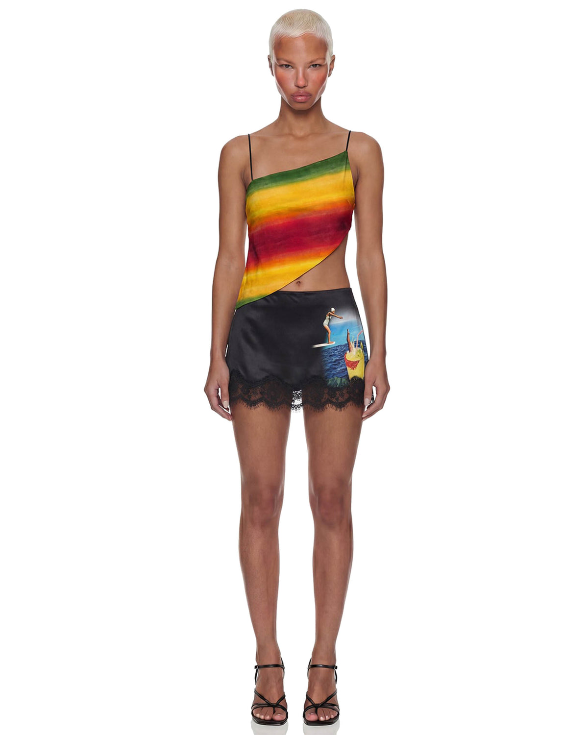 Modelo de frente com Mini Saia Cetim Renda Caipirinha preta de cintura baixa e barra de renda, combinada a top listrado colorido