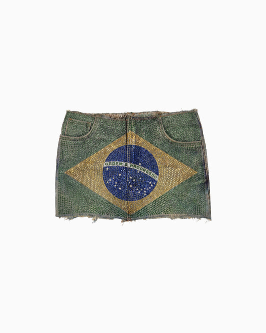 Mini Saia Strass Bandeira do Brasil em jeans verde coberta de strass, barra desfiada, vista frontal da peça solta