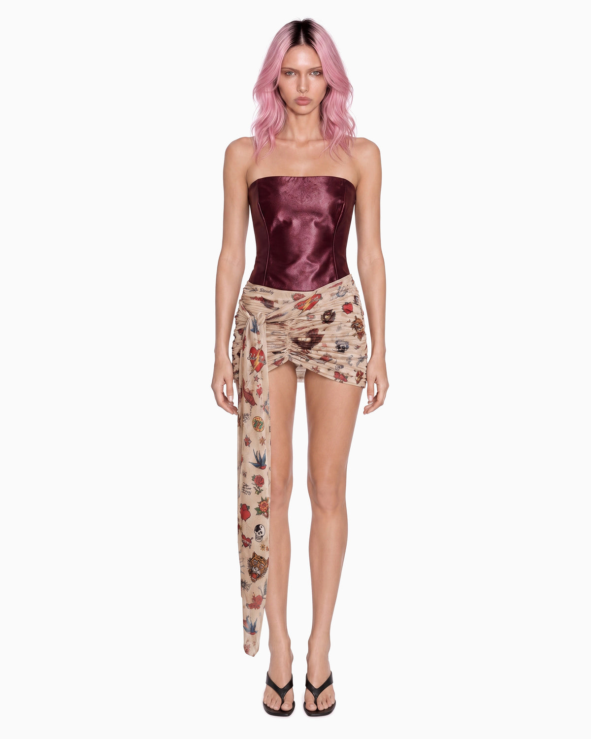Modelo de frente com a Mini Saia Transpasses Tule Tigre bege e corselet vinho, faixa comprida na lateral