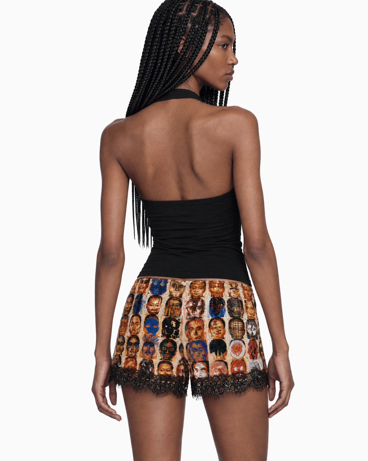 Modelo vestindo Mini Short Paetê Renda Rostos estampado, com acabamento em renda preta, vista de costas