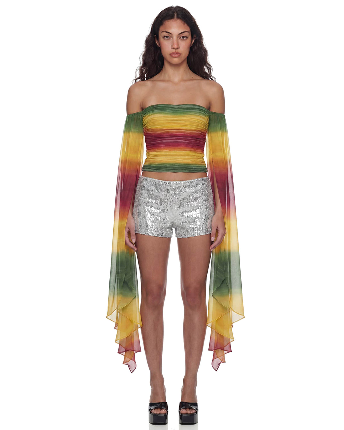 Modelo de frente veste o Mini Shorts Paetê Aura prata de cintura baixa com top ombro a ombro colorido