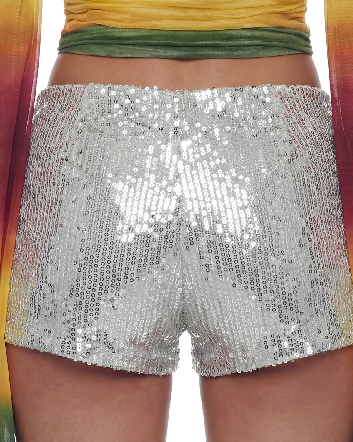 Detalhe das costas do Mini Shorts Paetê Aura prata na modelo, paetês reluzentes e caimento curto