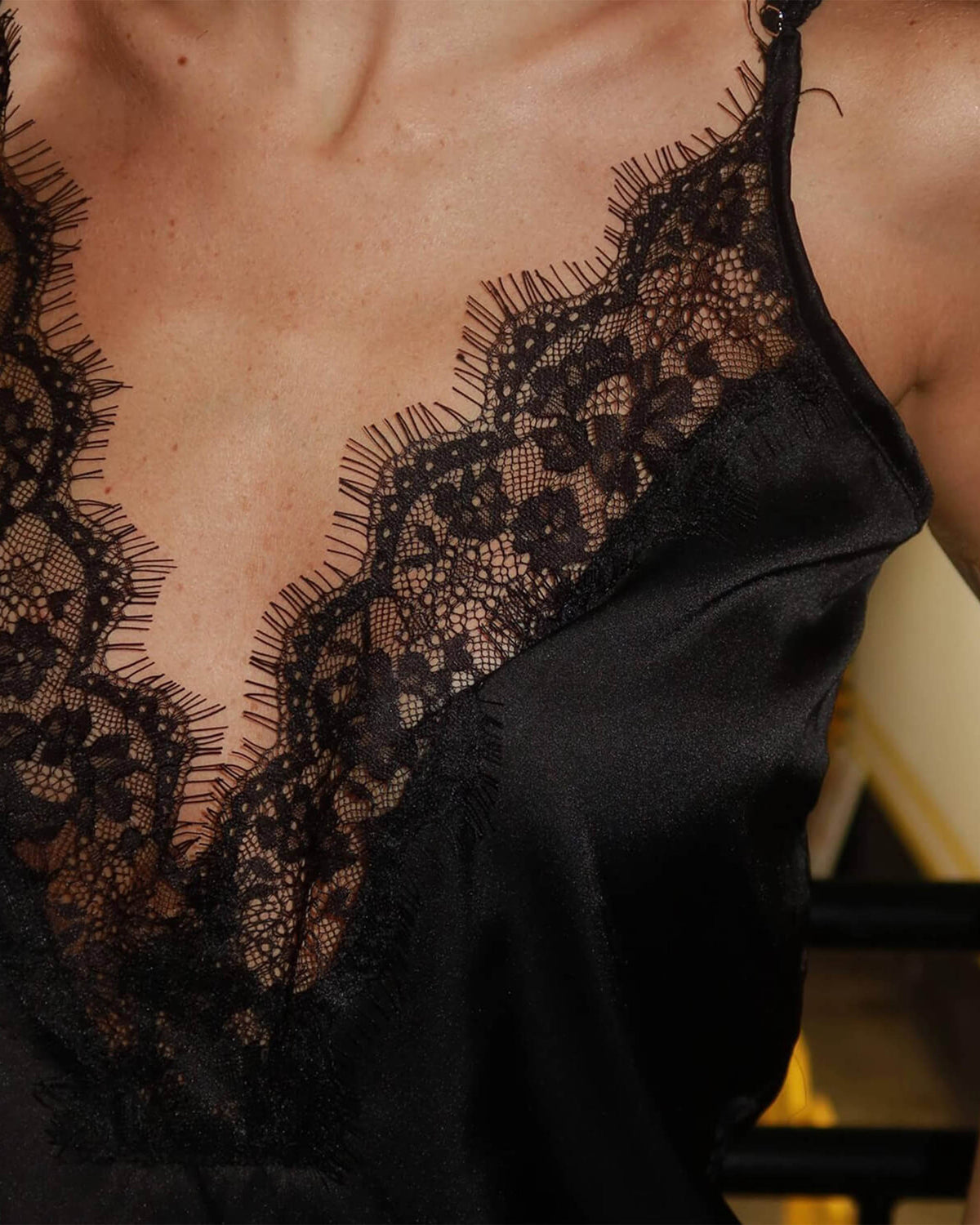 Detalhe da renda floral preta e do cetim no decote da Regata Afterparty vestida pela modelo