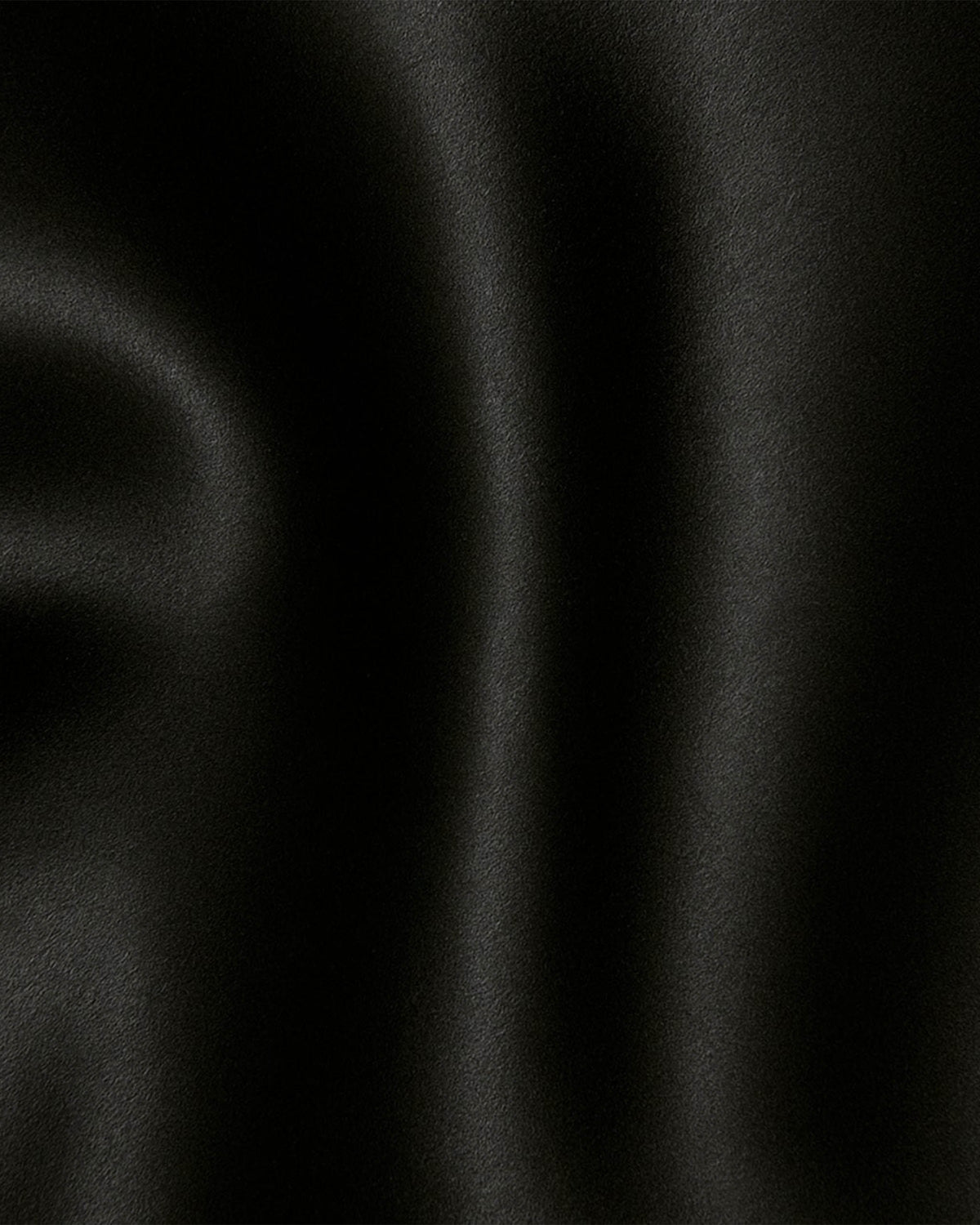 Detalhe do tecido acetinado preto da Regata Afterparty, com caimento fluido e brilho suave