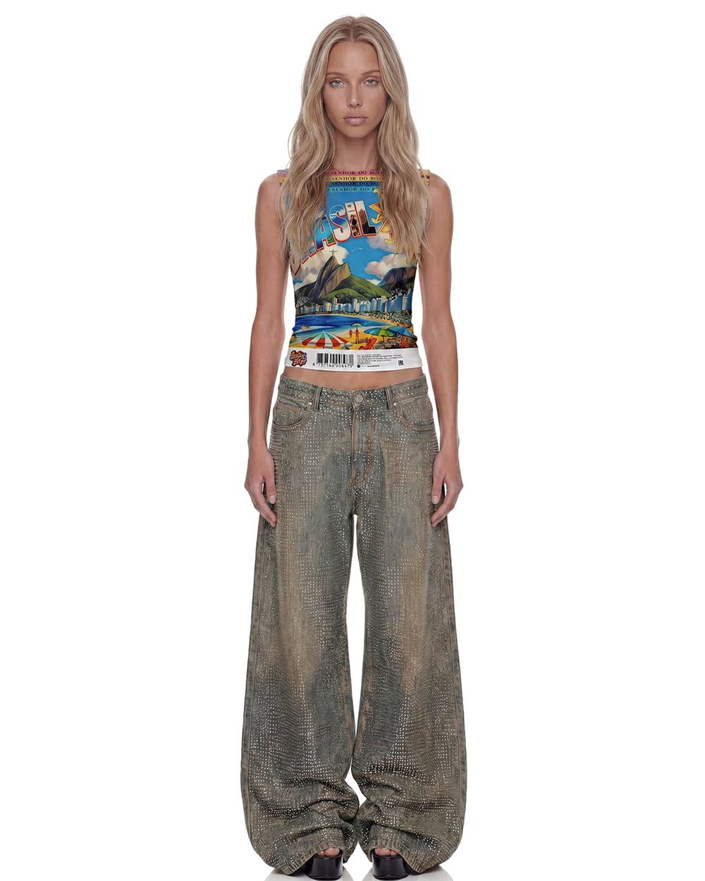 Modelo de frente veste regata Brasilidades cropped com estampa colorida do Rio e calça jeans larga