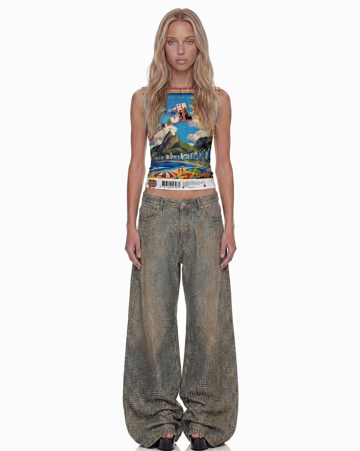 Modelo de frente veste regata Brasilidades cropped com estampa colorida do Rio e calça jeans larga