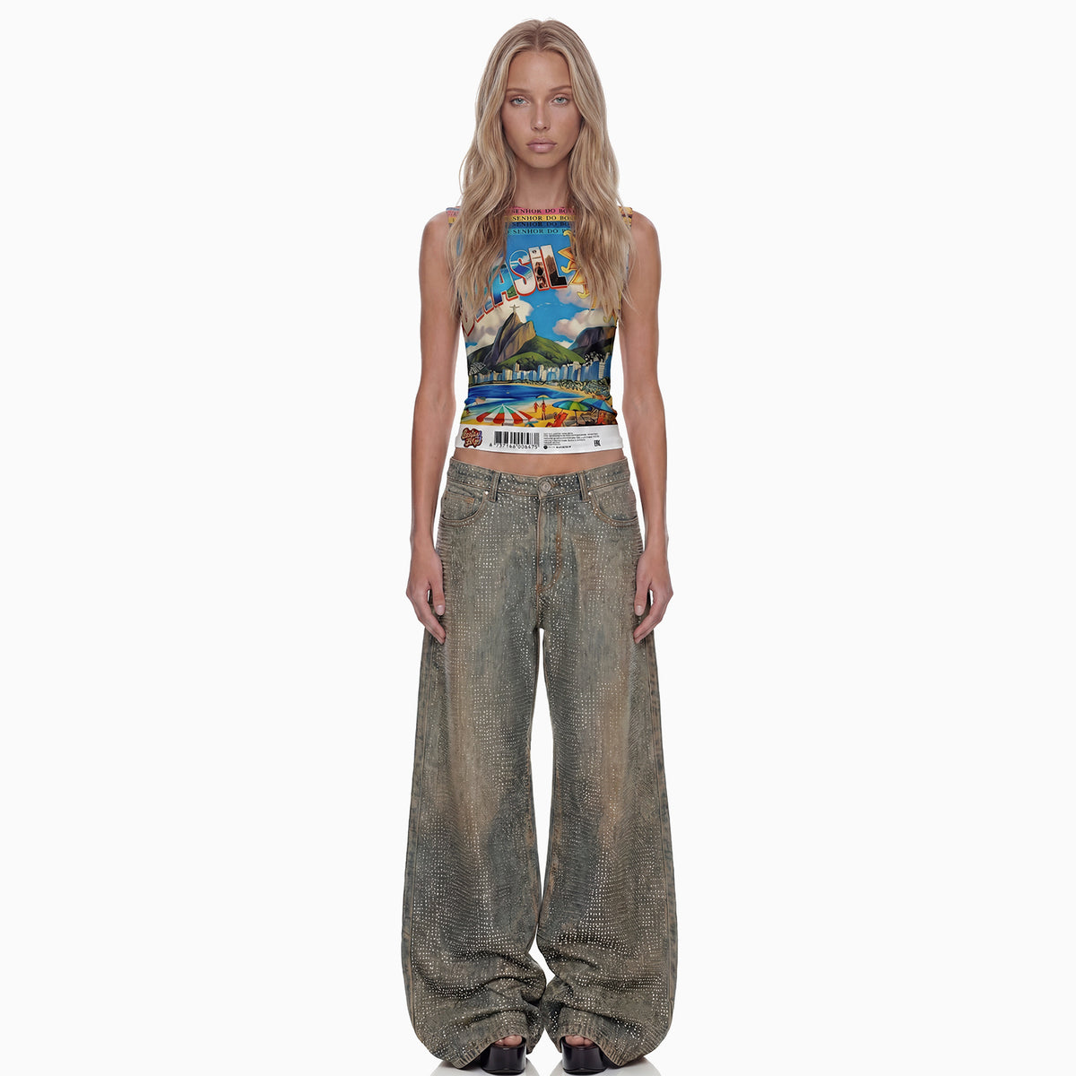 Modelo de frente veste regata Brasilidades cropped com estampa colorida do Rio e calça jeans larga