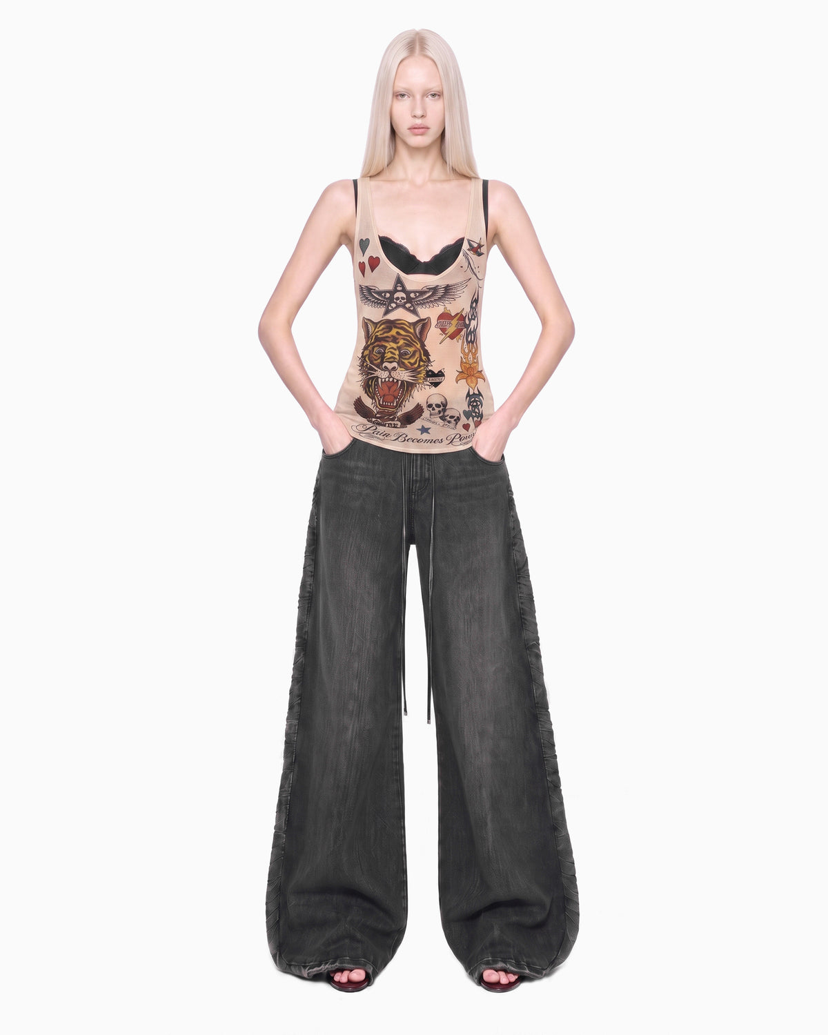 Modelo de frente com a Regata Cavada Tule Tigre bege, mãos nos bolsos da calça jeans larga escura
