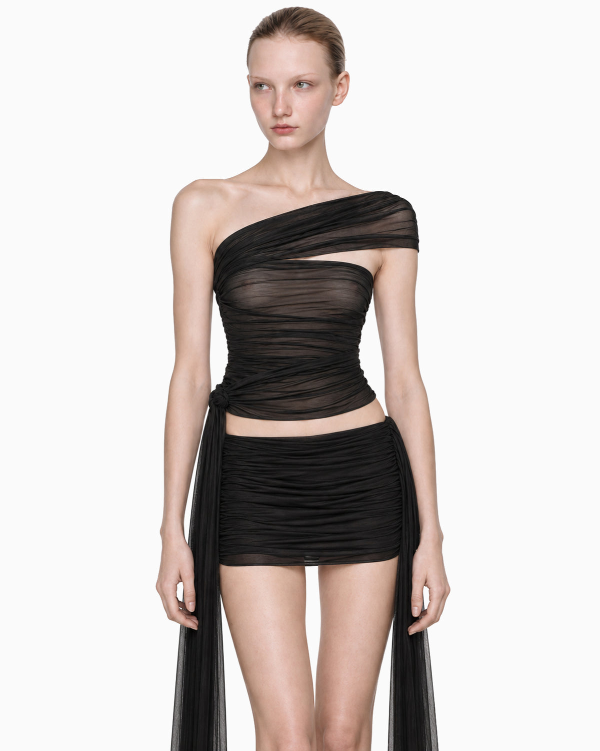 Modelo vestindo Top Faixa Lateral Tule preto, faixa larga no ombro e faixas longas soltas na lateral, detalhe frontal