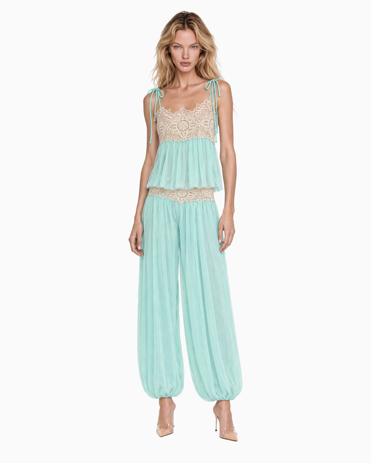 Modelo vestindo Top Tule Renda Alça Amarração acqua com busto em renda bege, combinado com Calça Tule Aladim Renda Bege, vista frontal de corpo inteiro