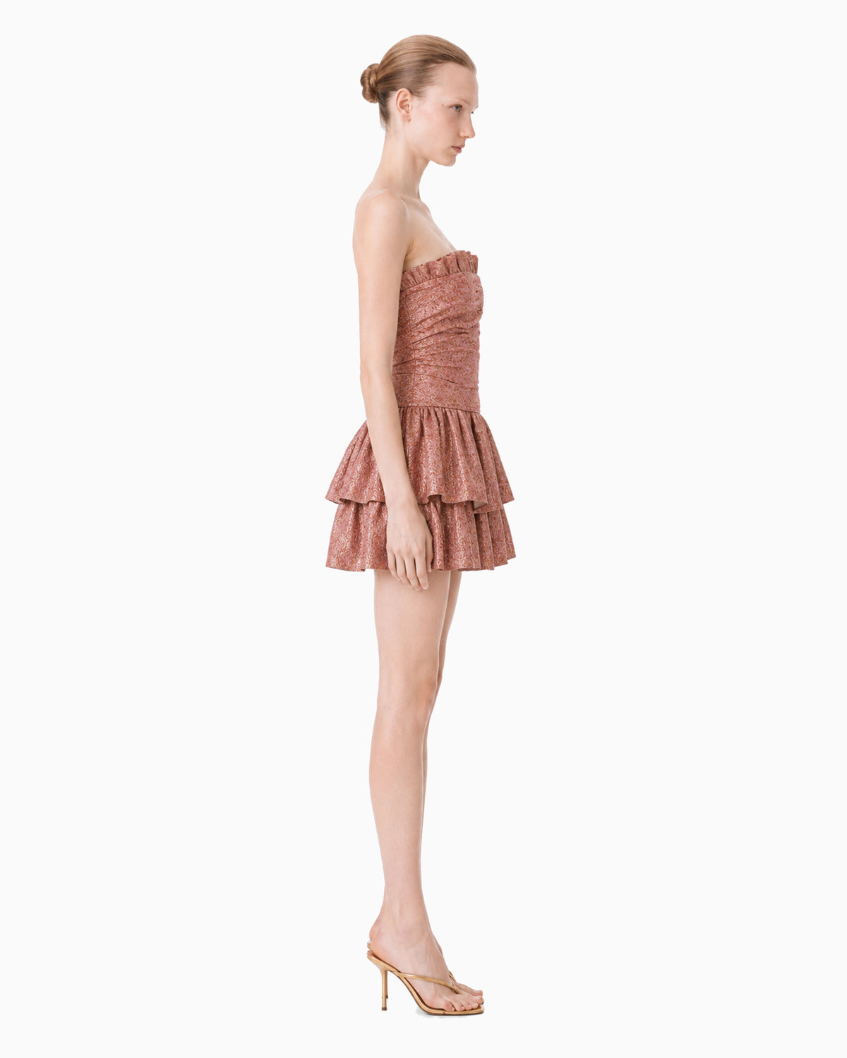Vista lateral do vestido curto tomara que caia rosé metalizado com saia em babados amplos