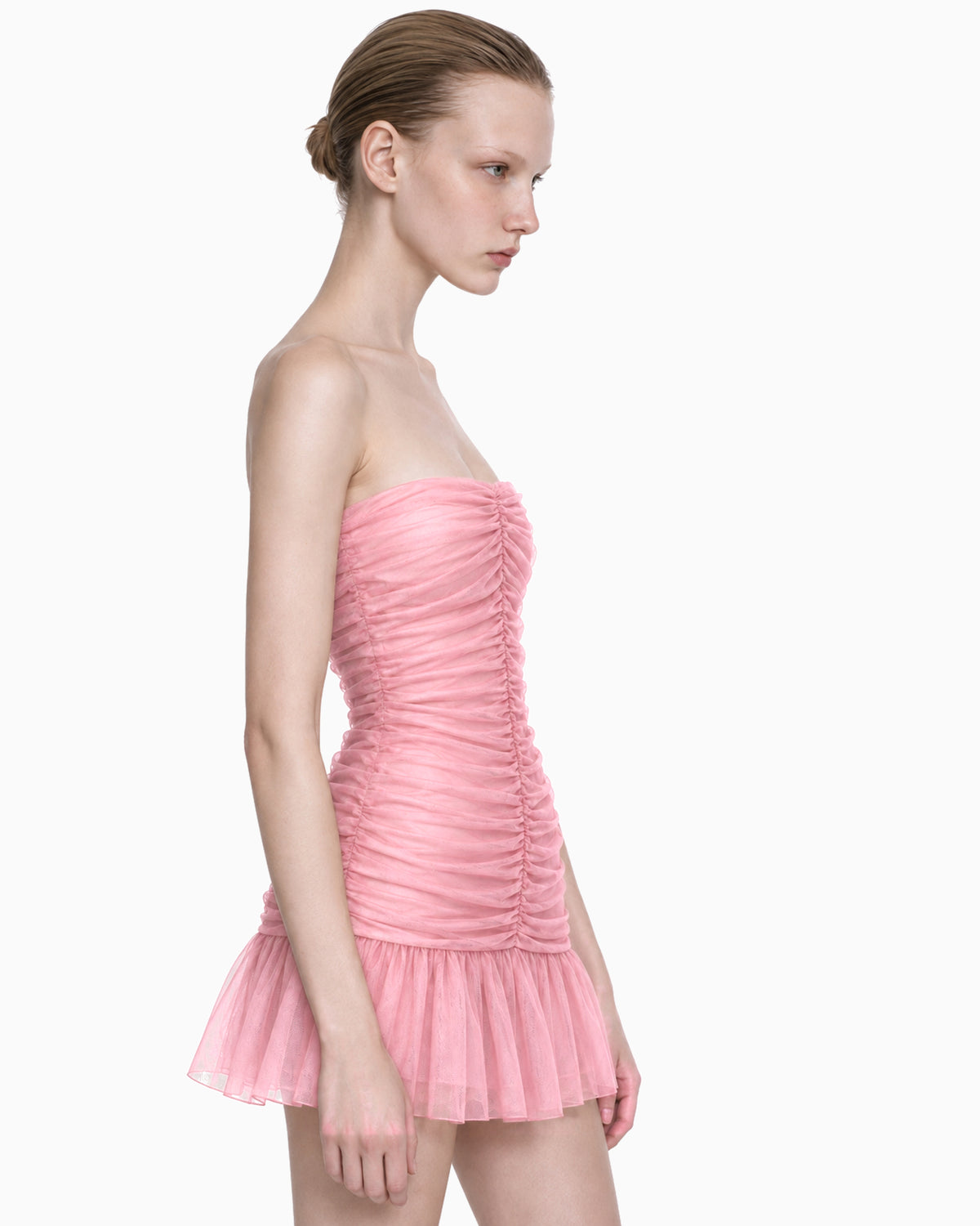 Modelo vestindo Vestido Curto Drapeado Tule Doll rosa, tomara que caia com corpo franzido e saia em tule, vista lateral