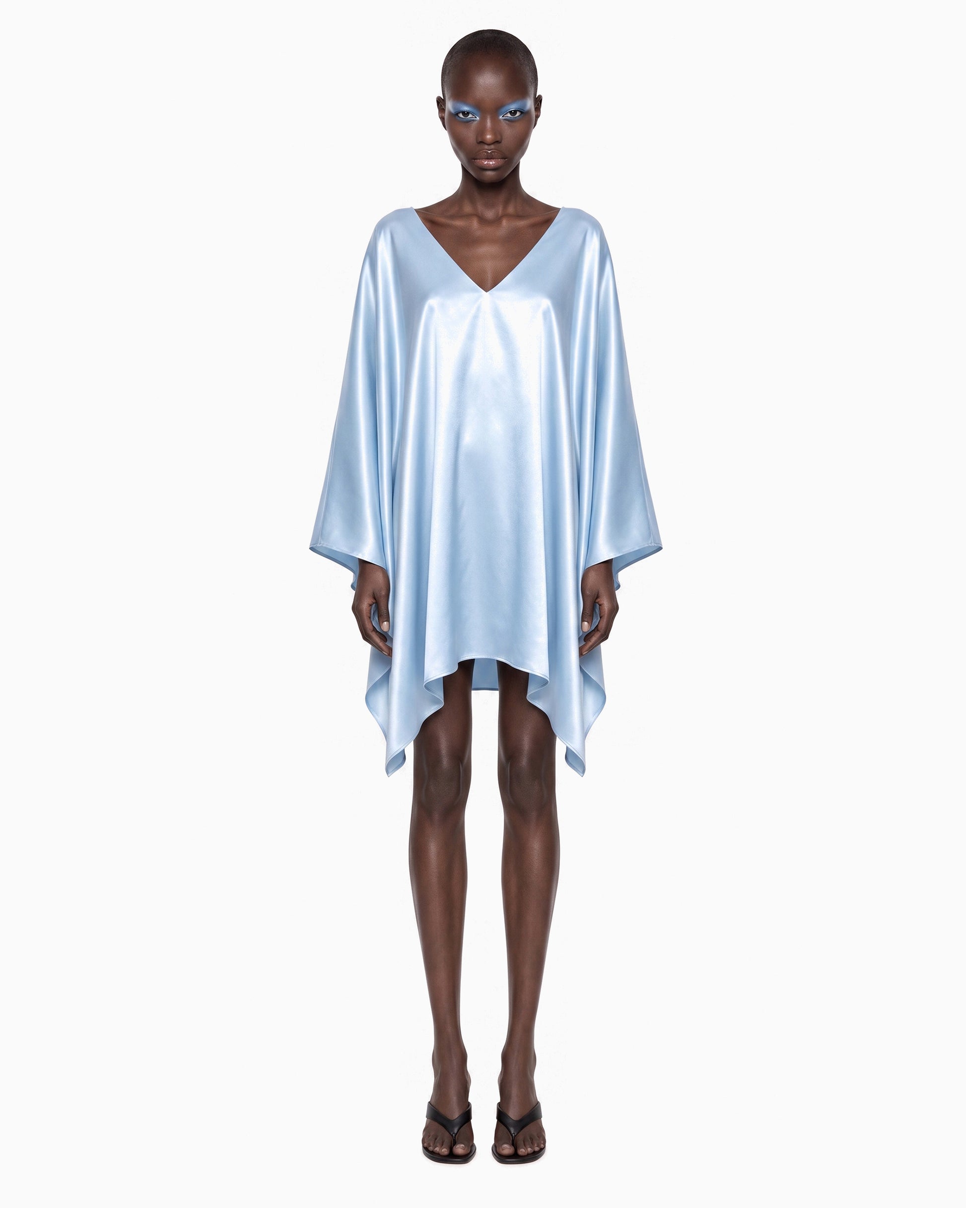 Modelo de frente com Vestido Curto Manga Morcego Ivo azul claro, decote V, mangas soltas e barra curta em pontas