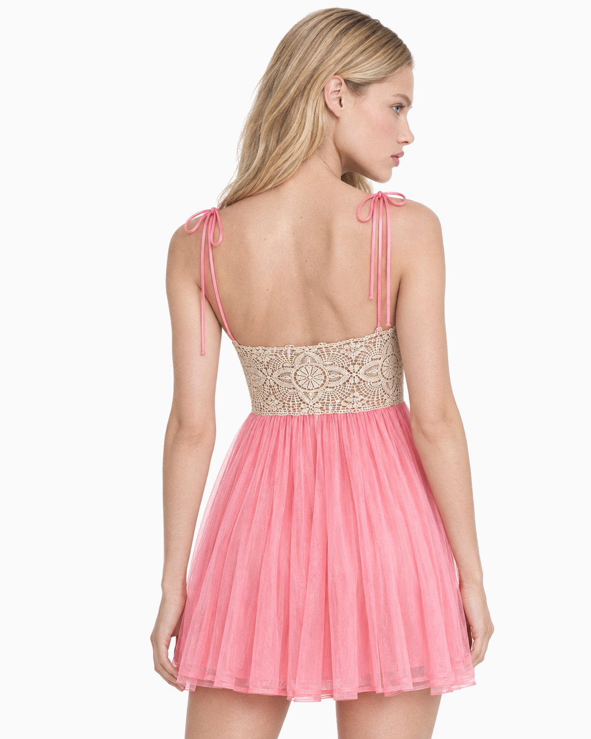 Costas do Vestido Curto Tule Renda Bege rosa na modelo, em vista de perfil com laços nas alças
