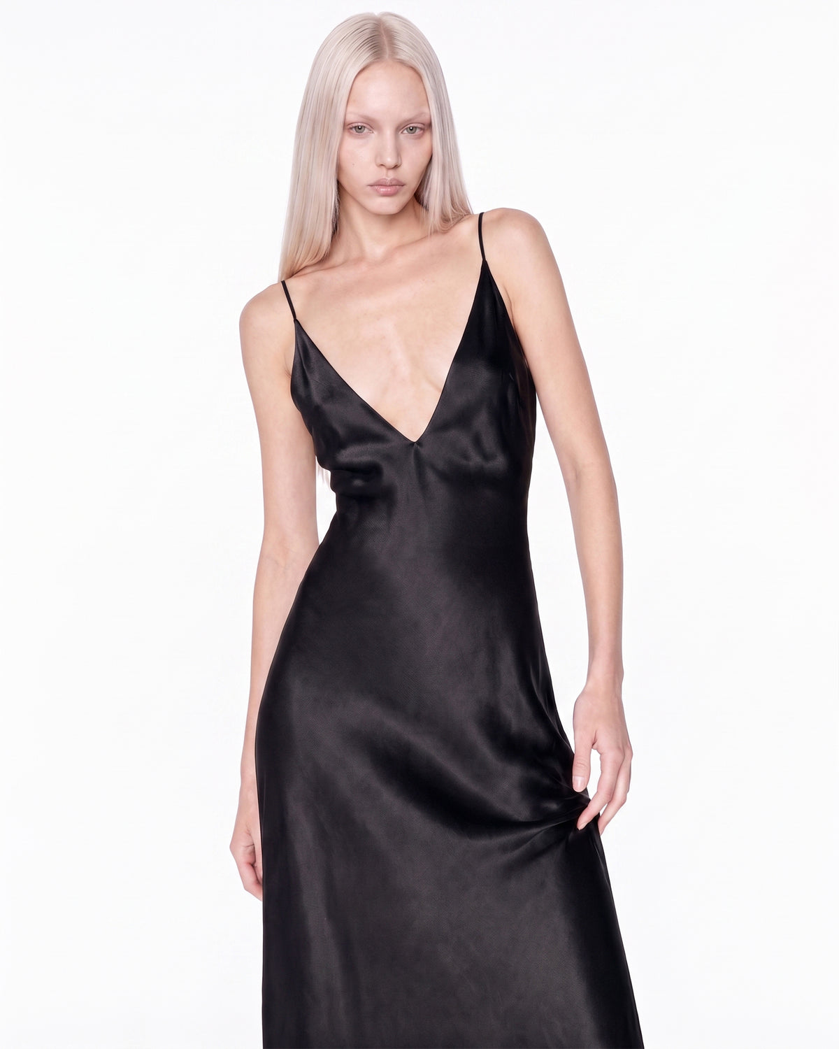 Modelo usando o Vestido Ivo preto em meio corpo, decote V profundo e saia rodando na altura do quadril