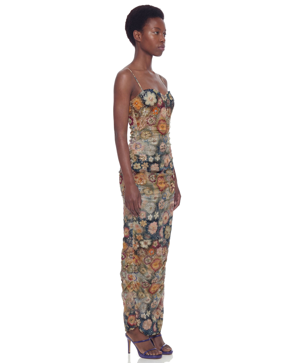 Modelo de perfil com Vestido Longo Tule Hibisco justo ao corpo, com flores bordadas e comprimento longo