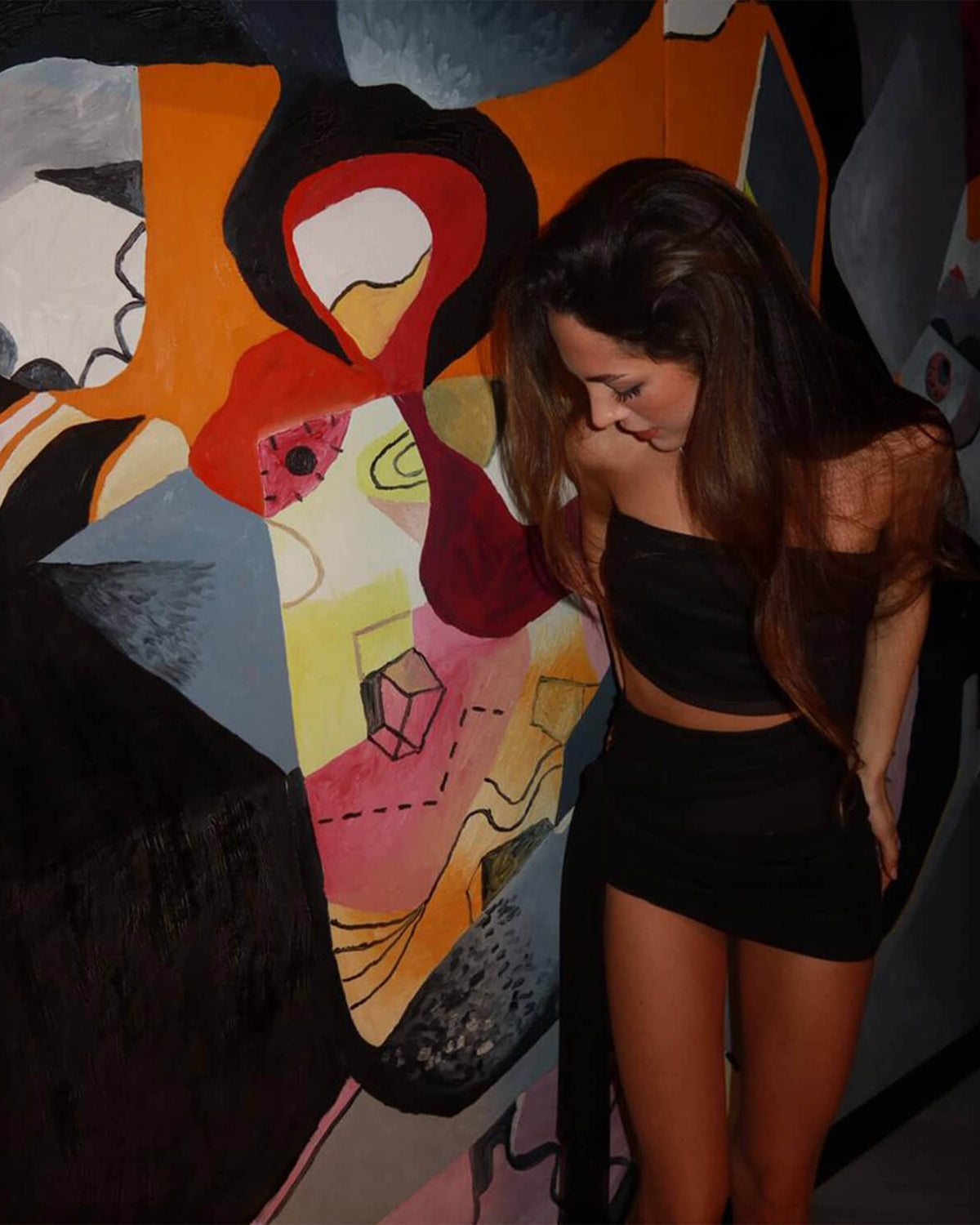 Modelo inclinada usa Vestido Siena preto tomara que caia com recorte na cintura e saia curta franzida